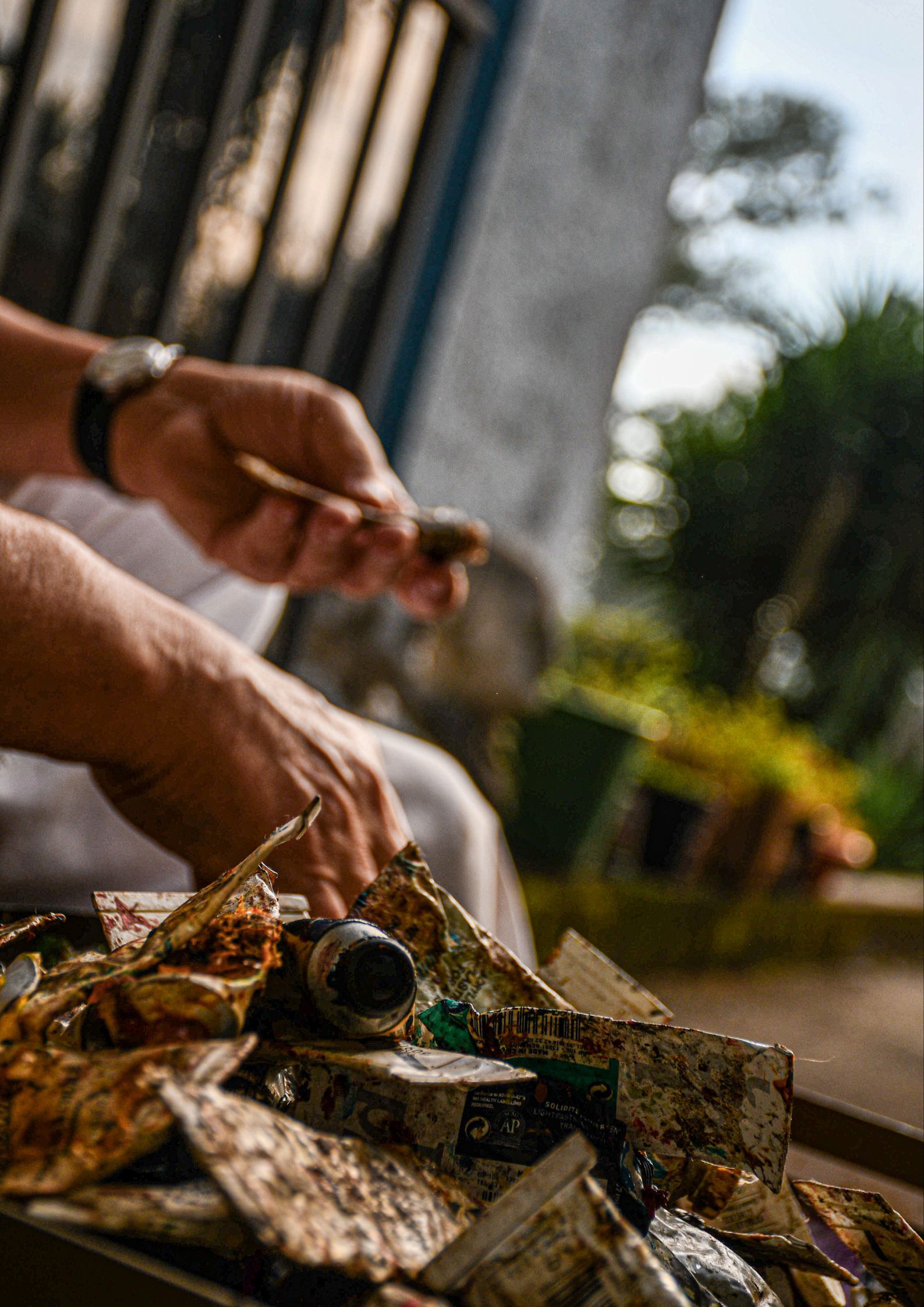 Artist's hands with paintbrush and paint tubes